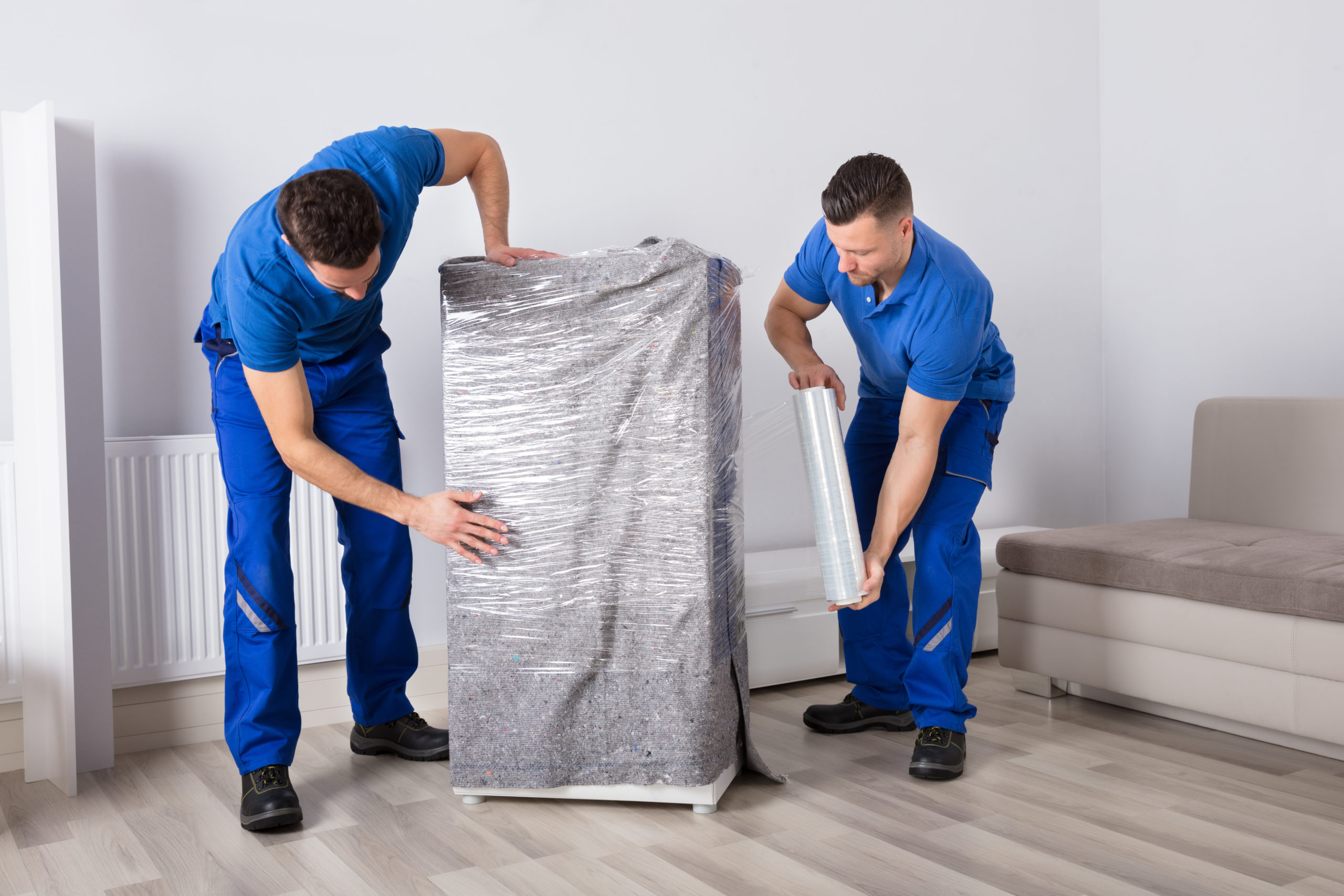 wo Young Male Movers Packing Furniture In Living Room